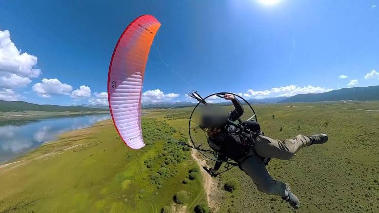 Powered paraglider pilot in flight over open country