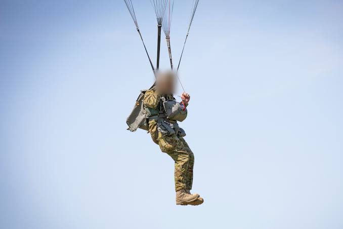Two paratroopers descending under canopy against a clear sky