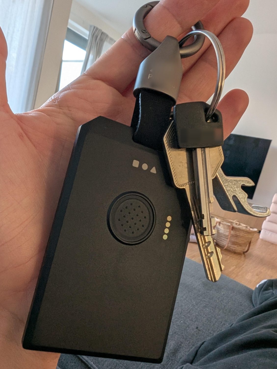 Card-format mesh tracker held in a hand, clipped to a keyring