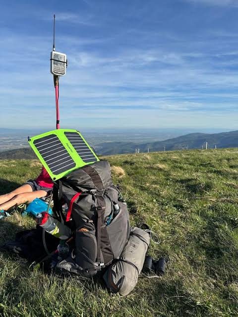 Mesh node and folding solar panel on a backpack at a hilltop