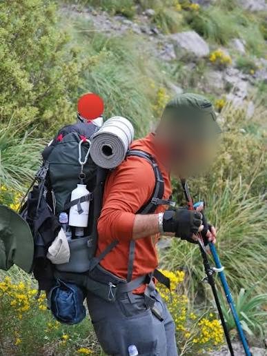 Trekker with a loaded backpack on a hill trail